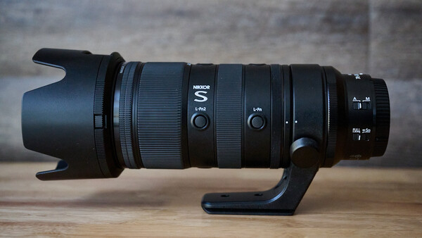 Nikon S-line telephoto zoom lens with hood and focusing mechanism mounted on wooden surface