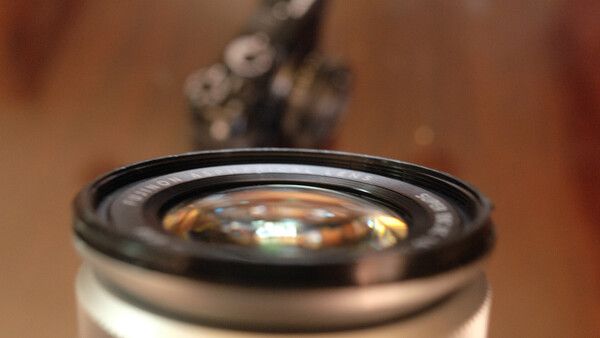 Close-up of a camera lens with shallow depth of field, showing glass elements and black barrel