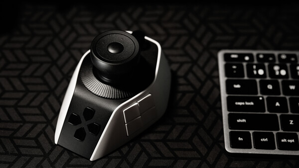 Ergonomic gaming mouse with side buttons displayed next to mechanical keyboard on textured surface