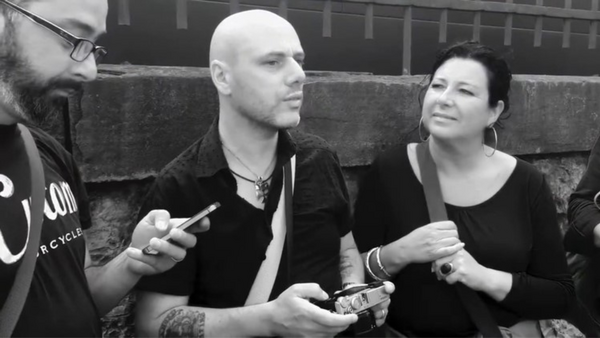 Three people sitting on concrete steps in black and white, engaged in conversation while holding mobile devices
