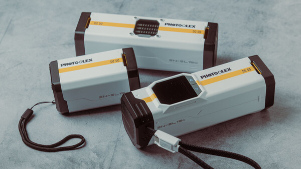Three Photoflex handheld reflectors with brown and white bodies arranged on a marble surface