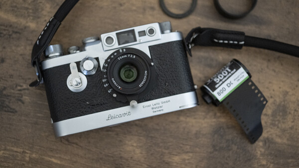 Voigtländer rangefinder camera with film canister and accessories on textured surface