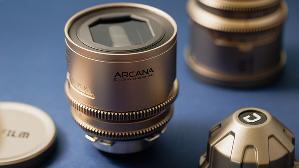 Arcana anamorphic lens with solar panel display and brass focus ring on blue surface