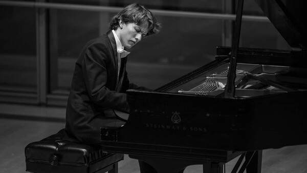 Pianist in formal attire performing at grand piano in black and white