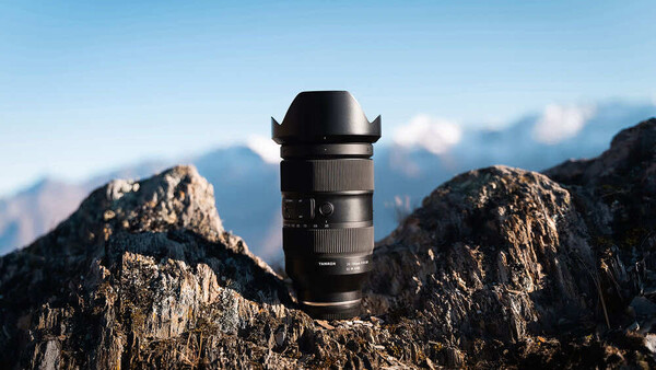Black telephoto lens positioned on a mountain peak with alpine landscape
