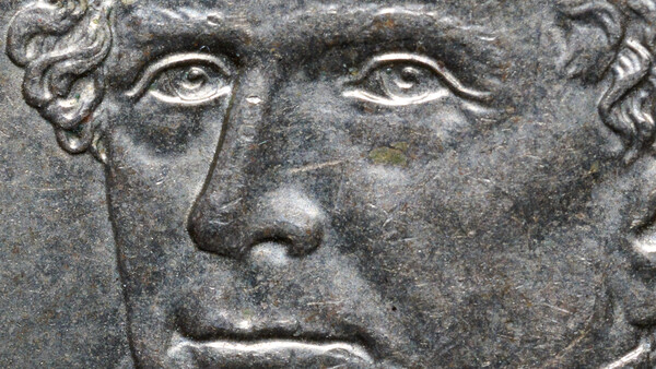 Stone relief sculpture of a man's face with classical features and curled hair