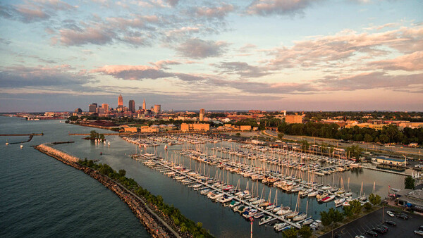 Aerial view of a large marina filled with sailboats at sunset with city skyline in background
