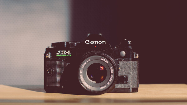 Canon AE-1 35mm film camera with Auto-Dial accessory on wooden surface