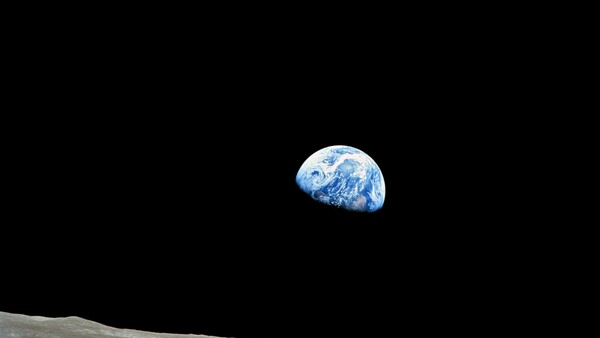 Earth rising above the lunar horizon against black space