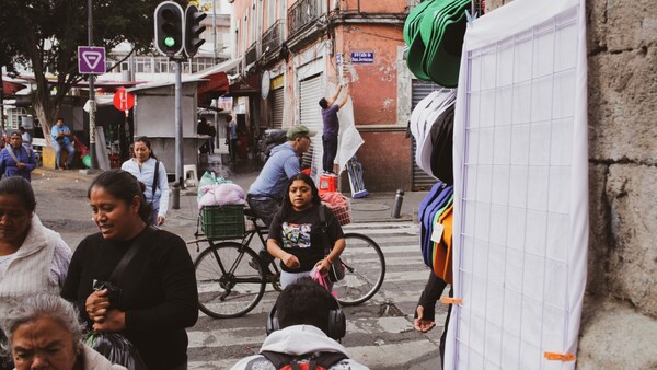 Busy urban street scene with pedestrians and a cyclist among market stalls and storefronts