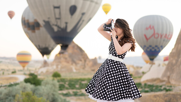 Woman in polka dot dress photographing hot air balloons in Cappadocia