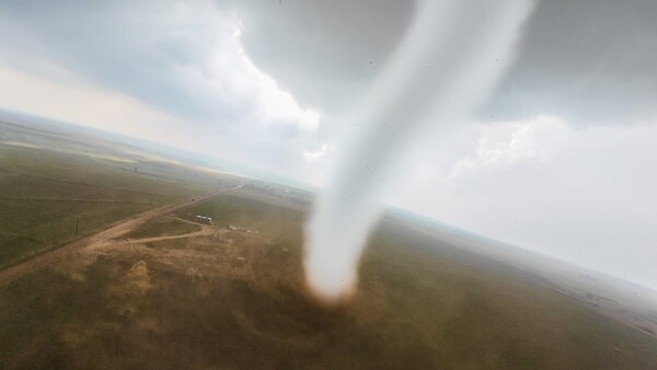 Tornado funnel cloud touching ground in rural landscape viewed from aircraft