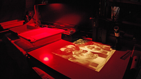 Screen printing setup with red illumination showing artwork under exposure light