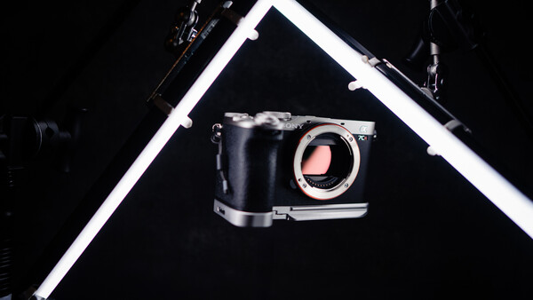 Mirrorless camera body displayed against black background with geometric white frame lighting