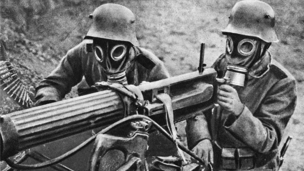 Two soldiers in gas masks and helmets operating a mounted machine gun
