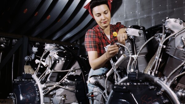 Woman in plaid shirt working on aircraft engine assembly in industrial setting