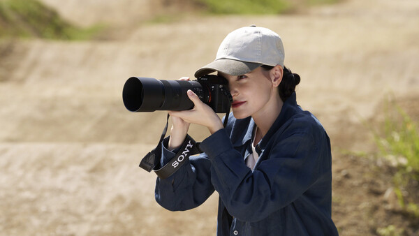 Photographer with camera and telephoto lens wearing cap and navy jacket