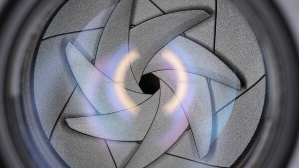 Camera lens aperture blades forming a spiral with iridescent blue and purple light reflections