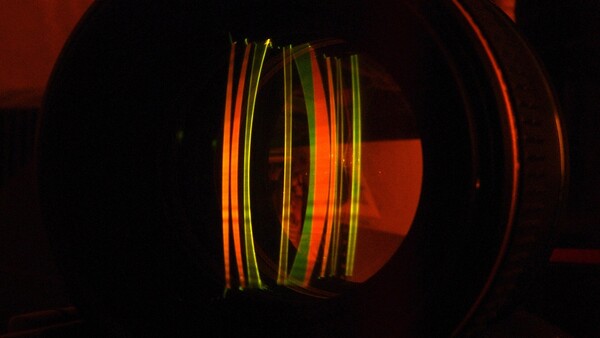 Colorful fiber optic cables glowing inside a dark cylindrical structure with warm red ambient lighting