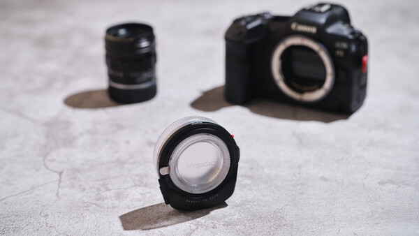 Canon R5 mirrorless camera body and three Canon RF lenses arranged on concrete surface
