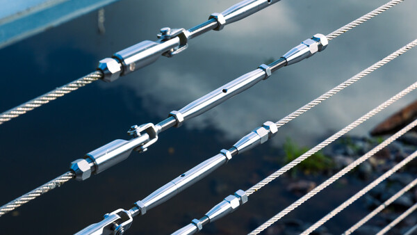 Close-up of stainless steel turnbuckles and tensioned cables on boat rigging