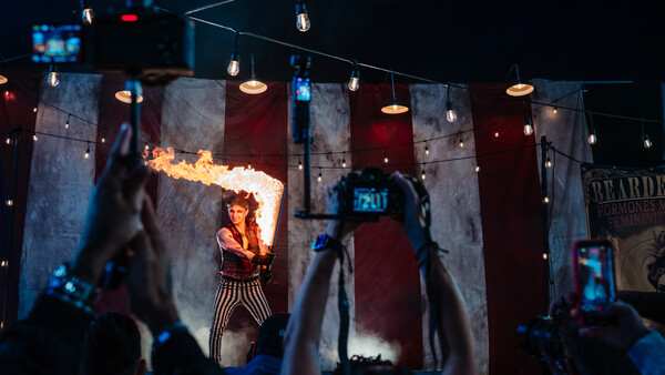 Fire breather performer on stage with audience members recording on phones
