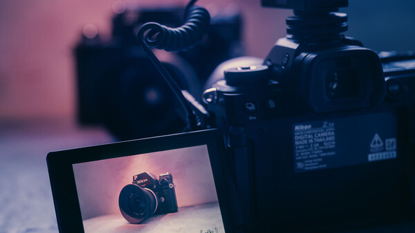 Digital camera displayed on monitor screen with camera equipment and lighting setup in background