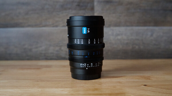 Black manual focus cinema lens with blue markings on wooden surface