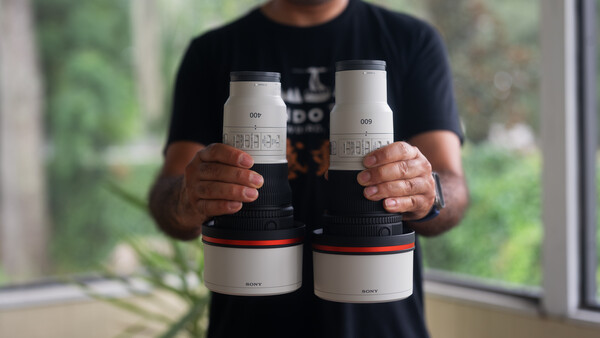 Photographer holding four white cylindrical lens cases with red accents