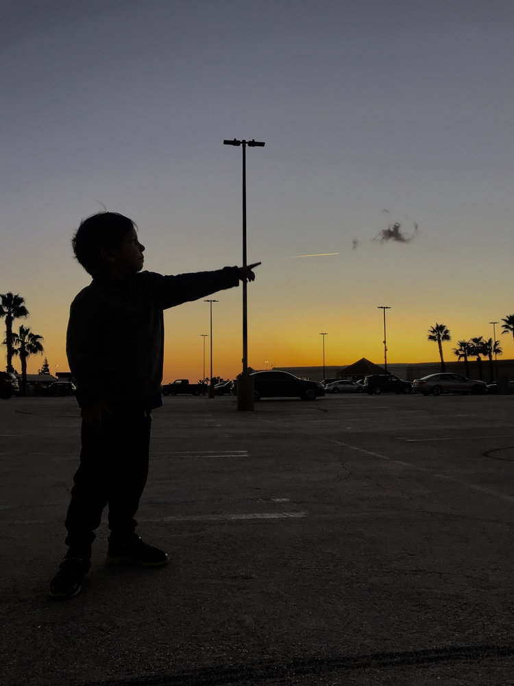 Little boy silhouette pointing at airplane during a sunset Little boy silhouette pointing at airplane during a sunset