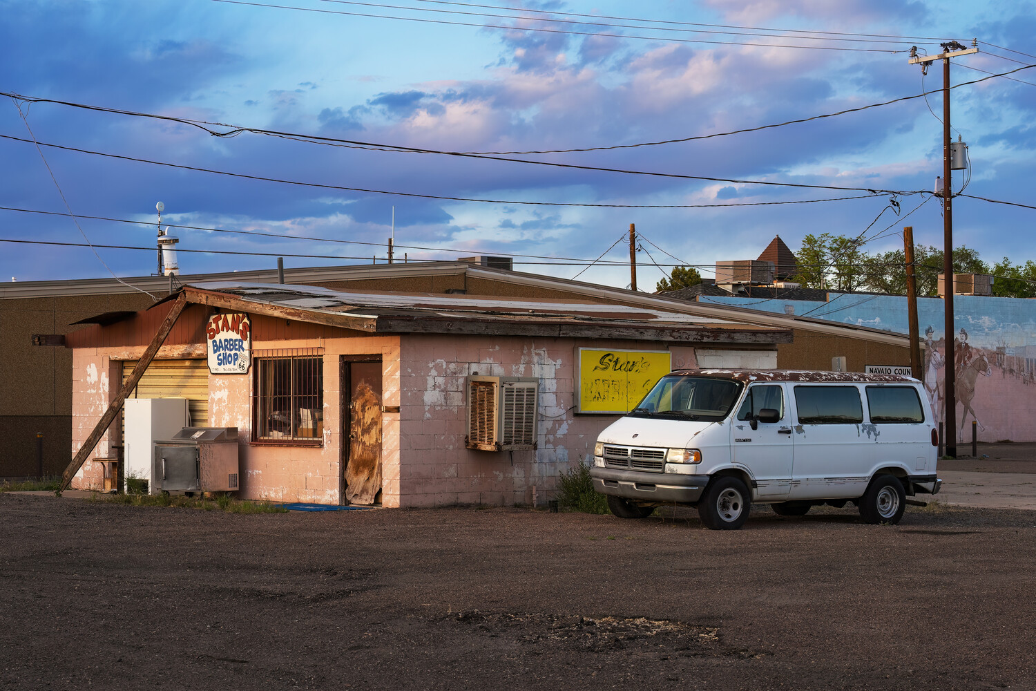 White van parked beside a weathered single-story commercial building at dusk