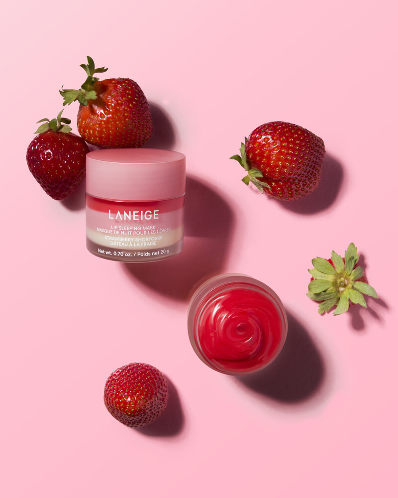 Laneige lip product jar with strawberries on a pink background in an overhead flat-lay product shot