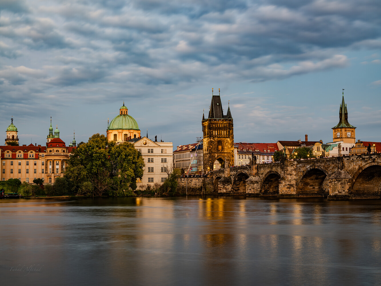 Charles Bridge and Prague skyline reflected in the Vltava River at golden hour