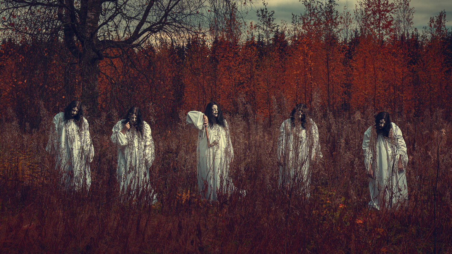 Five figures in white robes standing in a red autumn forest