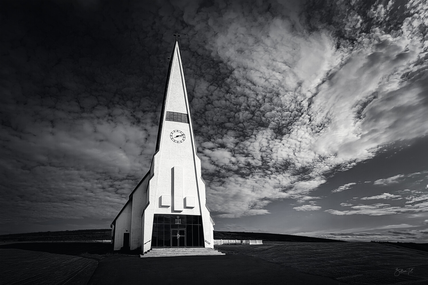 Modernist white church with sharp spire against dramatic cloudy sky