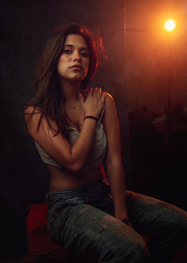 Woman in warm studio lighting gazes over shoulder against dark background