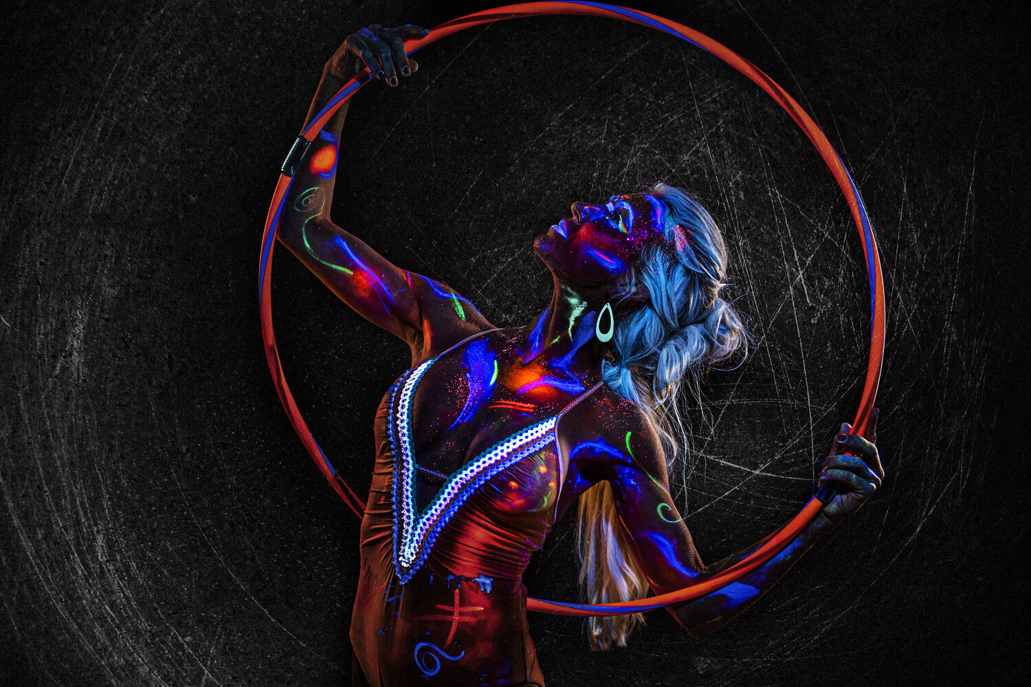 Dancer with body paint performing with LED light rope against dark textured background