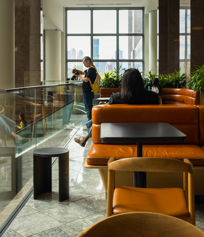 Modern interior with orange seating, glass railings, and large windows overlooking a city skyline