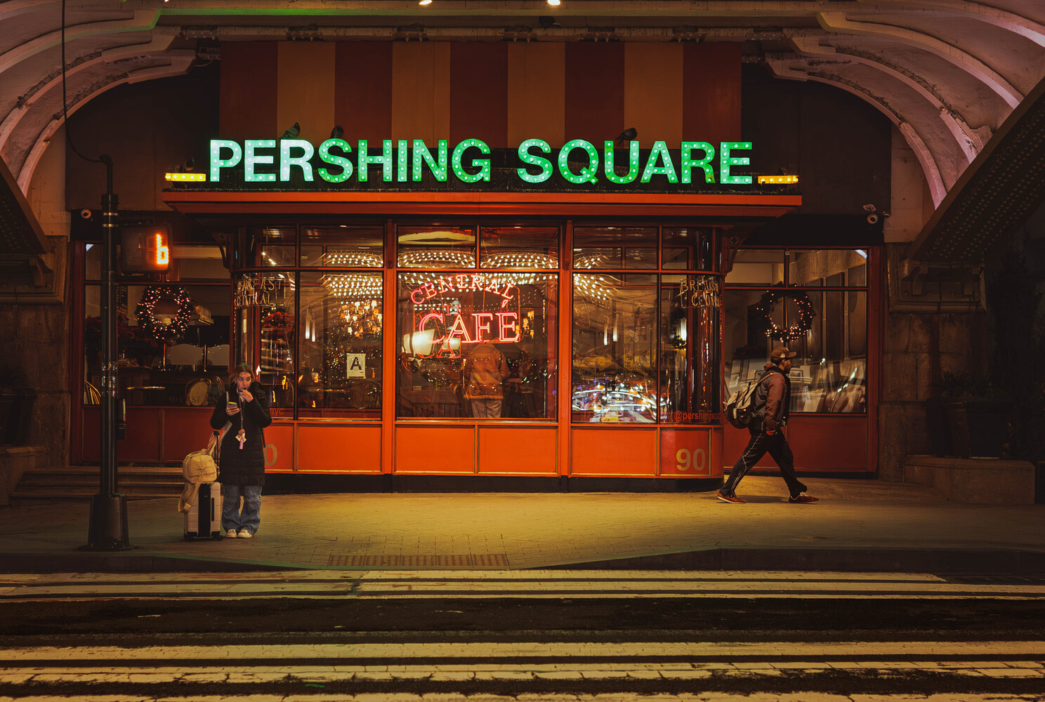 Pershing Square storefront at night with green neon signage and warm interior lighting