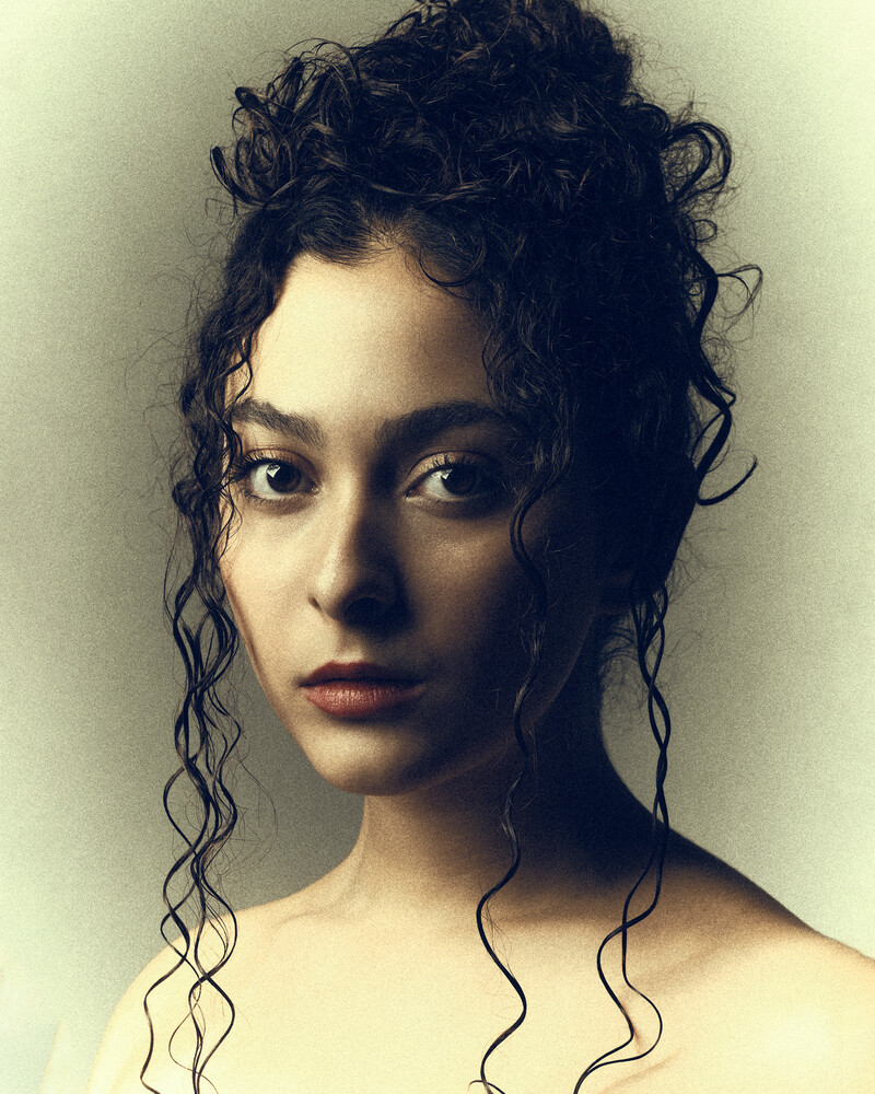 Portrait of a woman with voluminous curly dark hair against neutral background