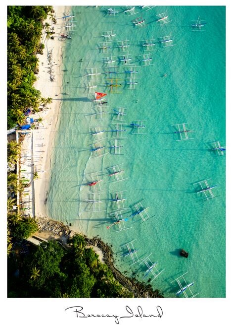 Aerial view of turquoise shallow water with scattered boats anchored near a sandy beach and tree-lined shore