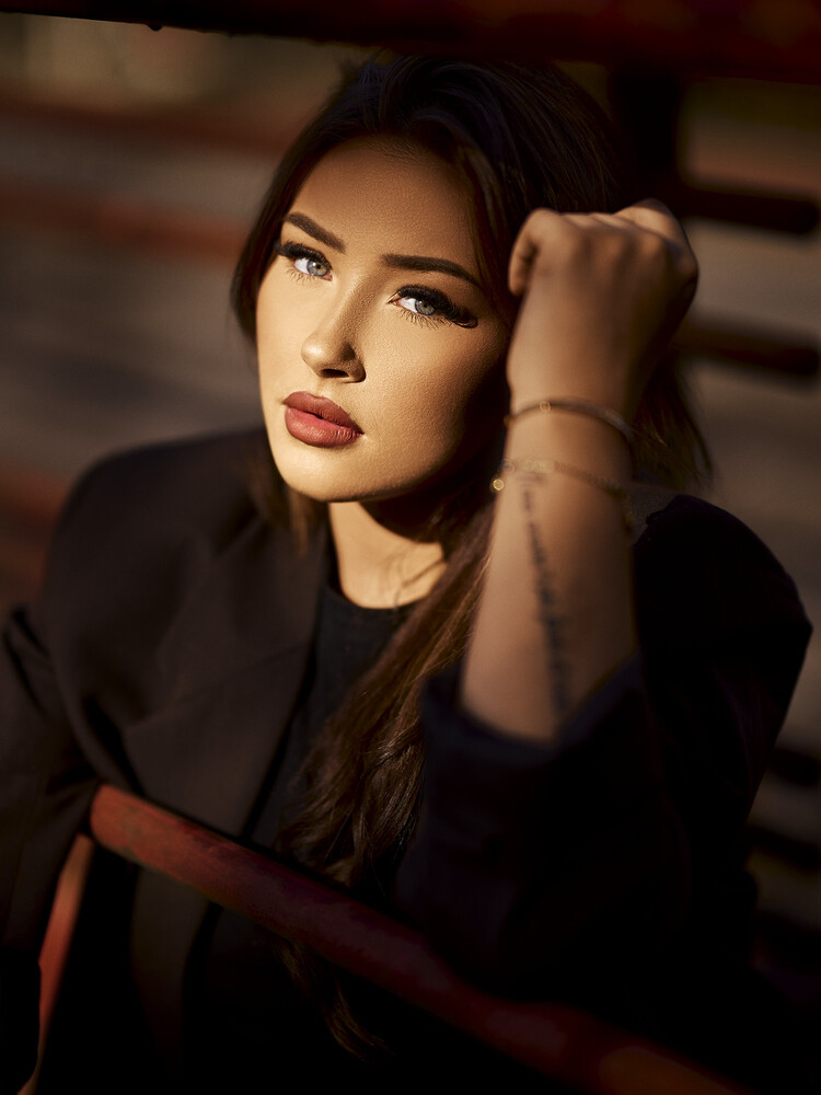 Woman in black blazer with dramatic makeup gazing thoughtfully to the side