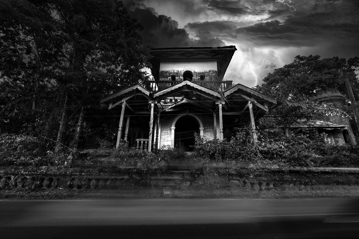 Abandoned neoclassical mansion with columned portico surrounded by overgrown vegetation under dramatic storm clouds