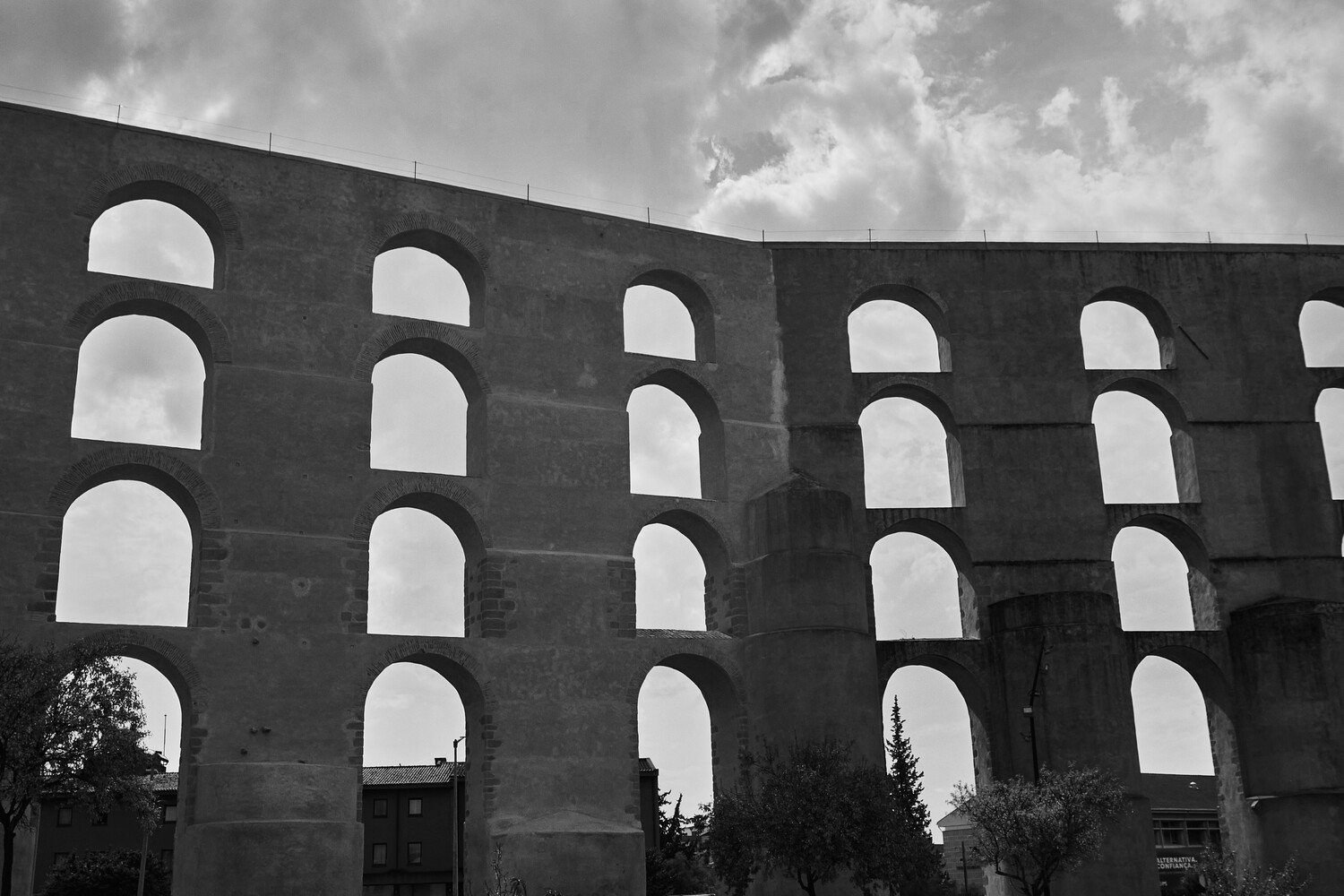Black and white photograph of a massive brutalist structure with rows of rounded arch openings