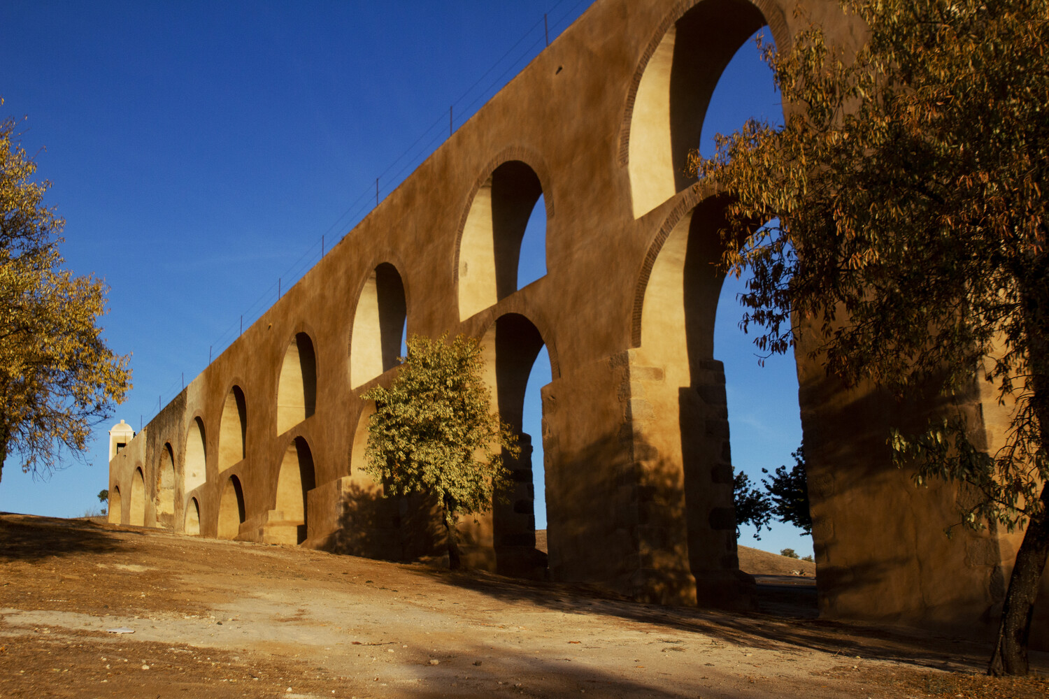 Ancient Roman aqueduct with multiple arches photographed against clear blue sky