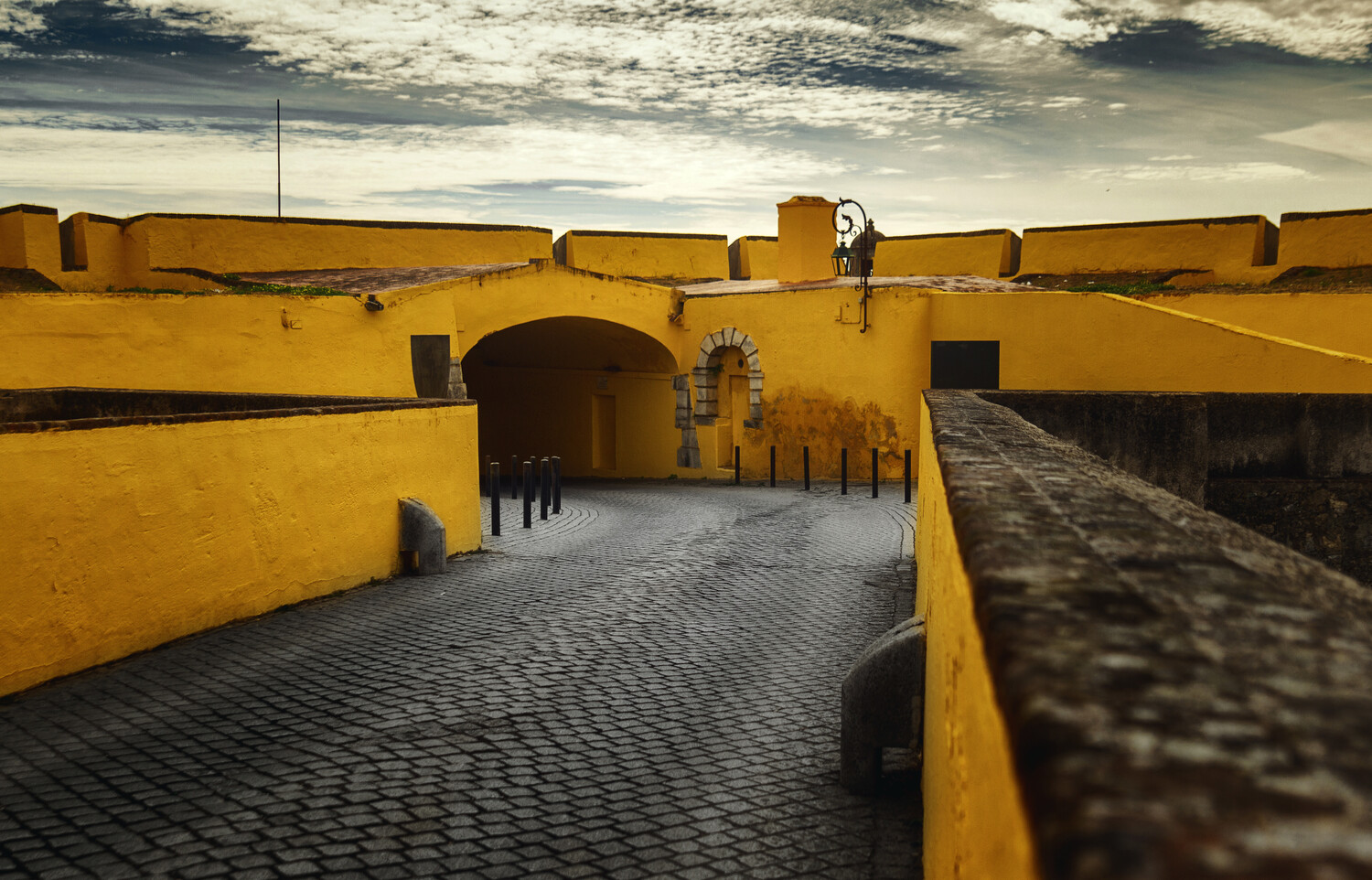 Vibrant yellow fortress with arched passageway and cobblestone path leading through tunnel