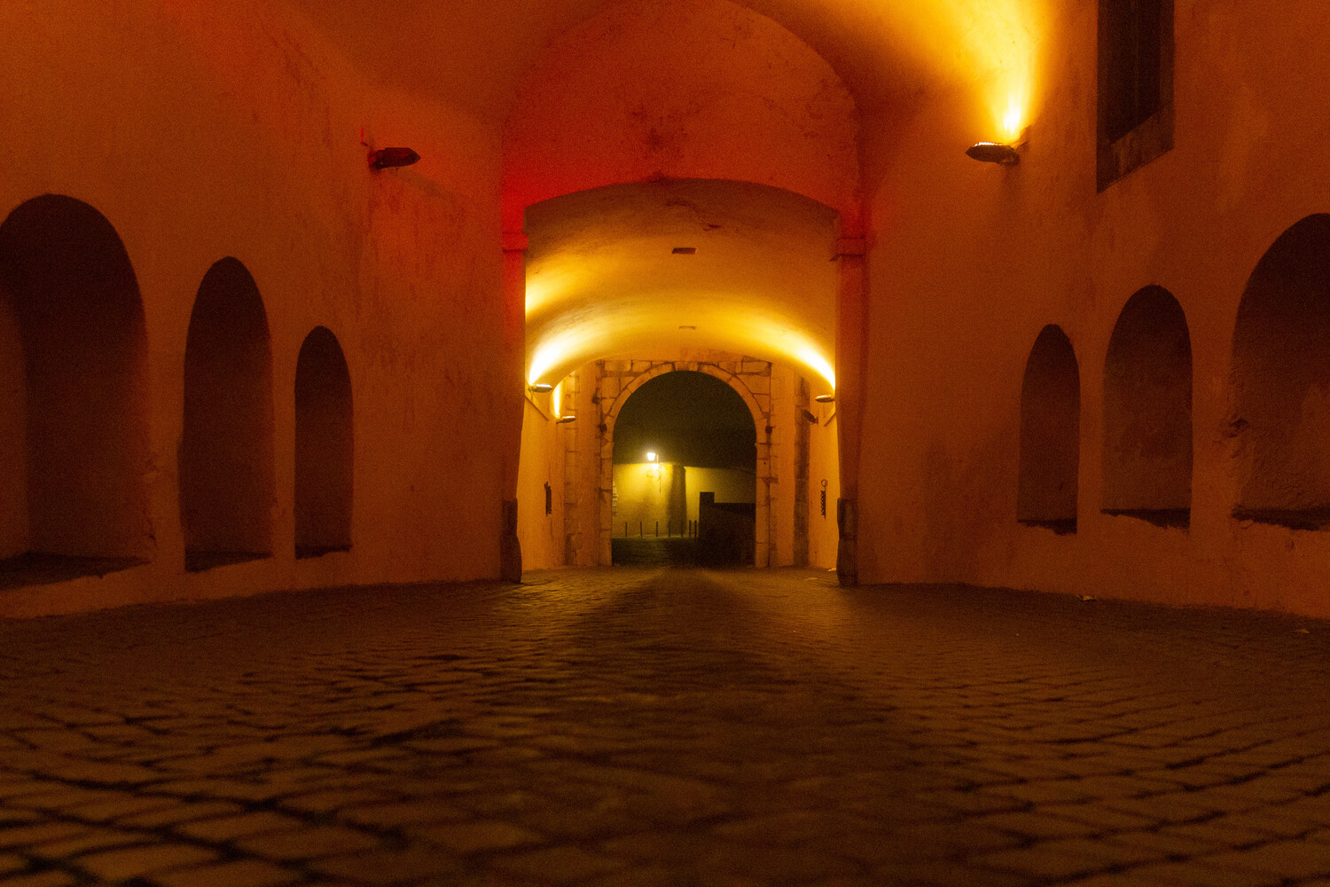 Warm-lit arched corridor with symmetrical doorways and textured floor