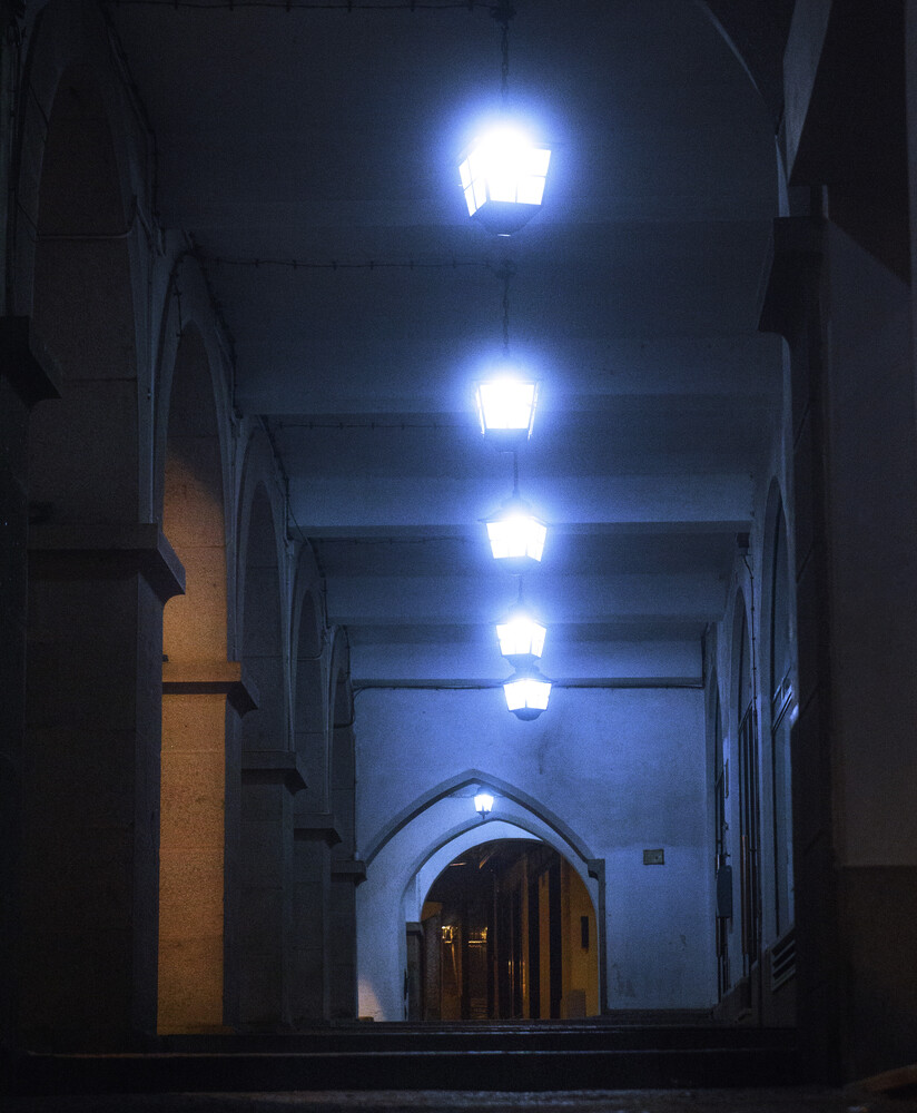 Symmetrical corridor with blue LED ceiling lights leading to an arched doorway