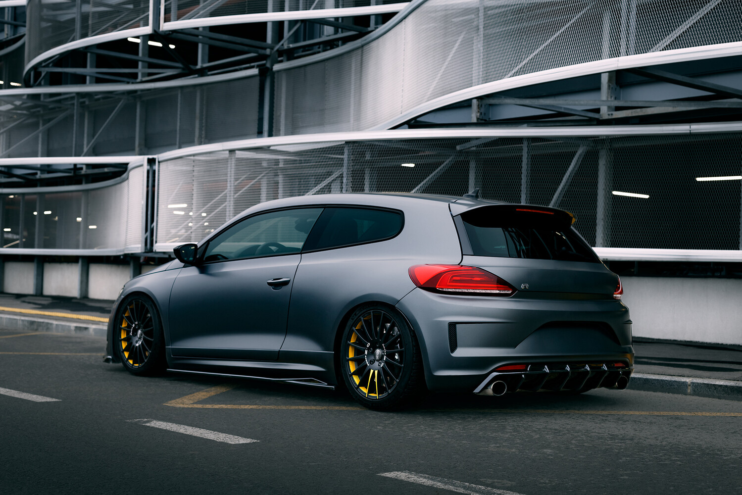 Modified performance hatchback with lowered suspension and gold wheels parked in modern garage