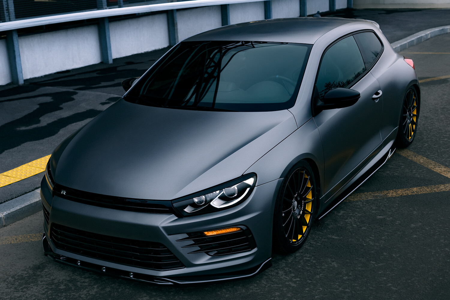 Modified sports car with aggressive front bumper and gold wheels parked in concrete garage